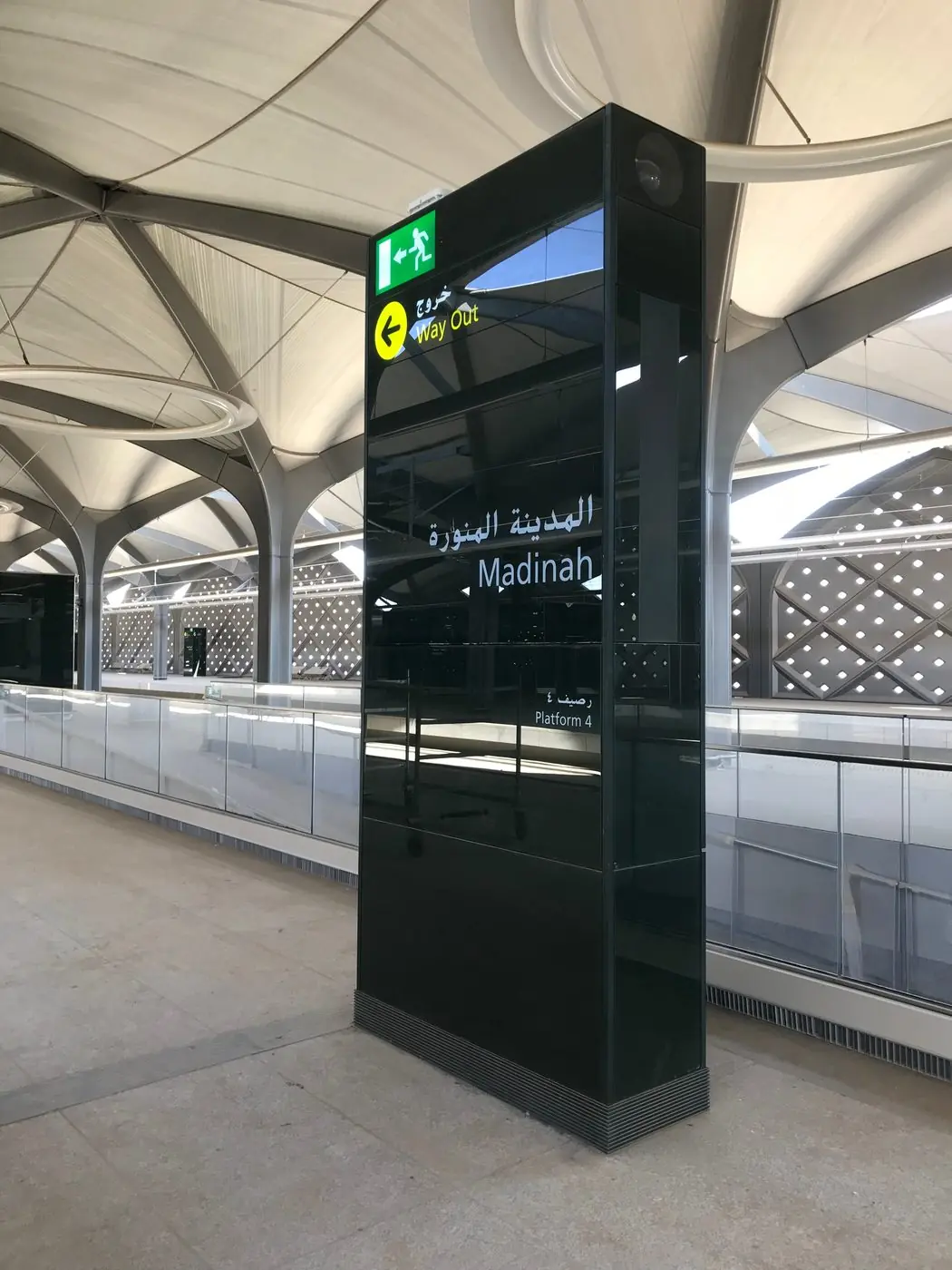 لوحة إرشاد زجاجية مضاءة من الخلف في صالة المحطة، تحمل كلمة «المدينة المنورة» بالعربية والإنجليزية تحت السقف المقبّب.