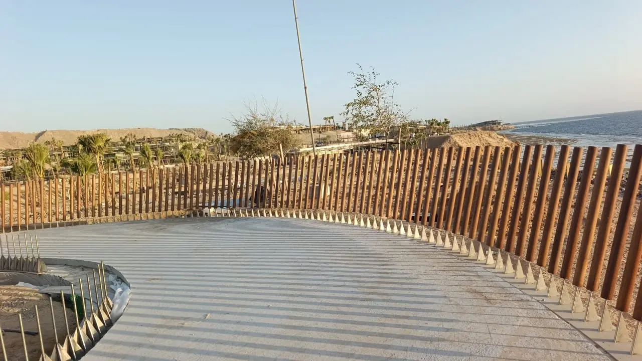 حاجز منحنٍ من الزعانف الخشبية يلتف حول شرفة جناح على الساحل.